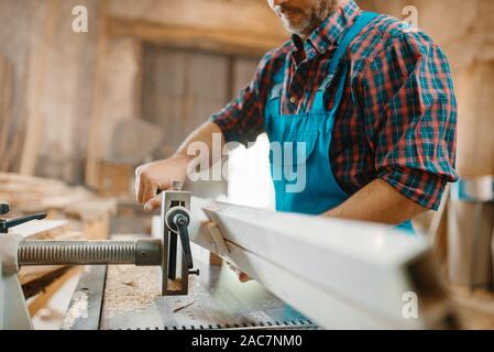 Carpenter works on plane machine, woodworking Stock Photo