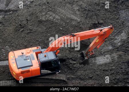 Crawler excavator scoops the earth with a bucket, top view. Earthmoving works, digging on a construction site Stock Photo