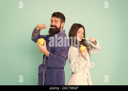 Oral hygiene. Couple bathrobes hold toothbrushes and apples. Personal hygiene. Couple in love cleaning teeth. Freshness and cleanliness. Keep teeth healthy. Healthy habits. Brush teeth every morning. Stock Photo