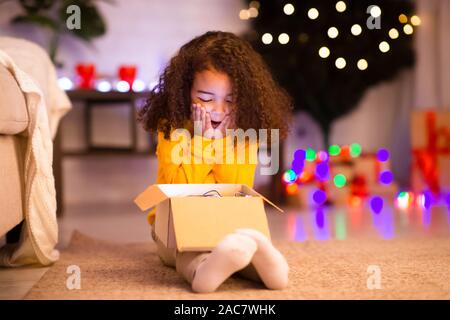 Shocked happy african american little girl enjoying Christmas gift Stock Photo