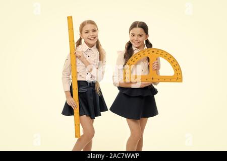 An important lesson. Little girls preparing for geometry lesson. Cute schoolgirls with measuring instruments at school lesson. Small children holding protractor and ruler for lesson. Stock Photo