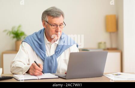 Elderly Man Using Laptop Working In Modern Office Stock Photo