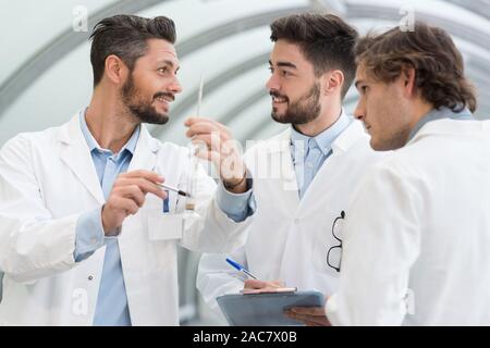three doctors in white coats having conversation at hospital hall Stock Photo