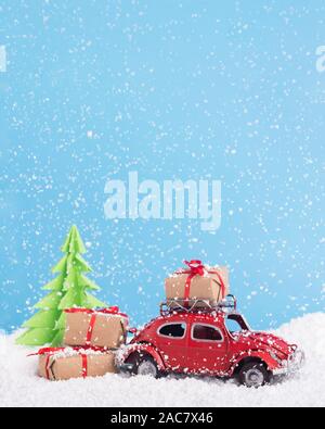 Retro car Volkswagen Beetle with presents and tree on snowy background Stock Photo