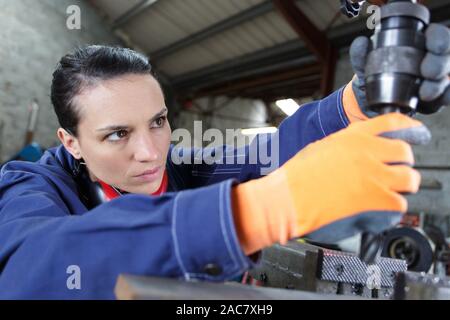 female apprentice using drill in factory Stock Photo