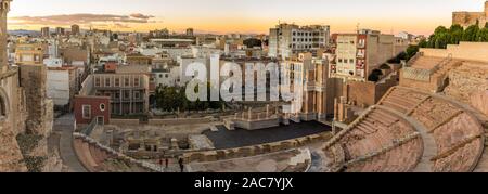 Aerial panoramic view of port city Cartagena in Spain with famous roman amphitheater. Beautiful sunset over the mountains. Wide angle lens panorama. Stock Photo