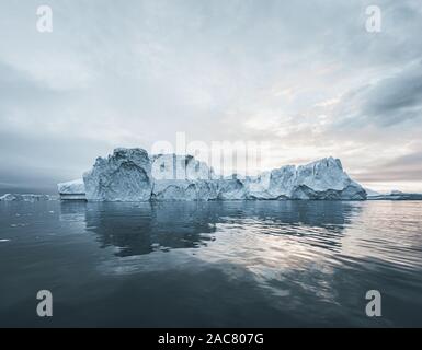 Bright sunny day in Antarctica. Full calm and reflection of icebergs in deep clear water. Travel by the ship among ices. Snow and ices of the Antarcti Stock Photo