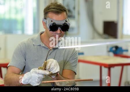 male engineer using a gas torch wearing protective goggles Stock Photo