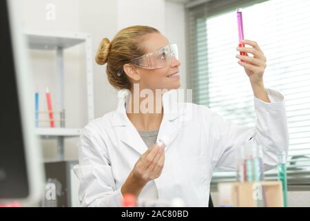 female technician looking at liquid in glass beaker Stock Photo