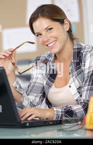 portrait of happy female computer technician using laptop Stock Photo