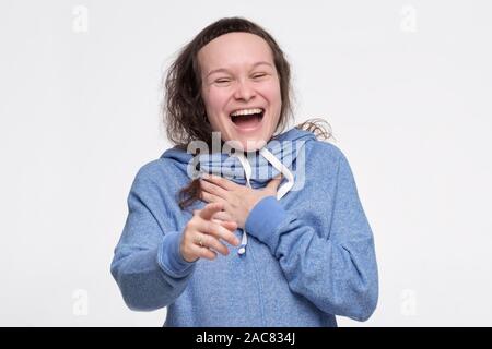 Caucasian female teenager in blue clothes laughing at you pointing with finger. You are so funny. Studio shot Stock Photo