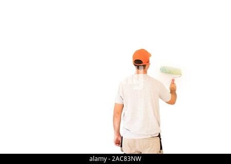 Rear view shot of young man using paint roller while painting white wall. Isolated on white background. Stock Photo
