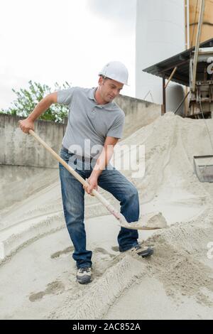 man takes a shovel of sand Stock Photo