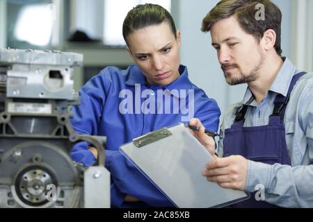 portrait of engineer and apprentice examining component in factory Stock Photo