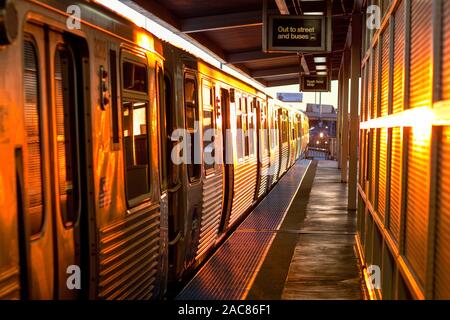 A Chicago Transit Authority Orange Line train arrives at the Ashland Ave station in Chicago at sunset. Stock Photo
