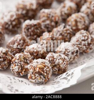 White plate full of delicious raw protein balls. Healthy sweets for sport people. Homemade dessert. Raw sweets made of nuts, coconut, dates and cacao Stock Photo