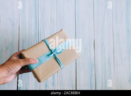 hand of Asian man holds brown paper gift box with copy space, view from the top Stock Photo