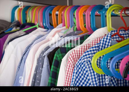 Children clothes on hangers in a room. wardrobe with boy's clothes on hangers. Shopping and consumerism concept. Dressing closet with clothes arranged Stock Photo