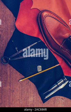 Shoemaker's work desk. Tools and leather at cobbler workplace. Man classic brown shoes and leather shoemaking tools and set of leather craft tools . S Stock Photo