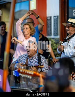 Close up of musician playing ukelele and singing passionately outside a bar in Garachico, Tenerife, Spain on 23 November 2019 Stock Photo