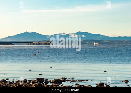 Some larger merchant Vessels and looking down over the old Power station jetty at Inverkip to Arran in the far distance as the cold mist rises from th Stock Photo