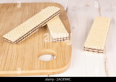 Group of three whole sweet chocolate biscuit wafer on bamboo cutting board on white wood Stock Photo