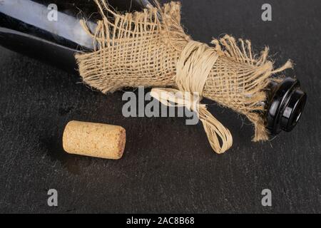 One whole common wine cork  with glass bottle with straw rope on grey stone Stock Photo