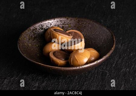 Lot of whole sweet brown toffee in glazed bowl on grey stone Stock Photo