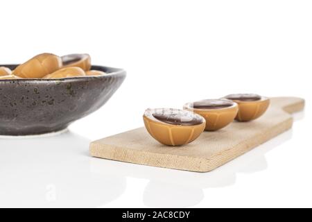 Lot of whole sweet brown toffee on wooden cutting board in glazed bowl isolated on white background Stock Photo