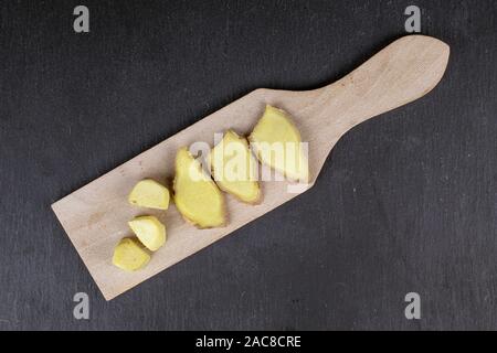 Group of three slices three pieces of fresh brown ginger on wooden cutting board flatlay on grey stone Stock Photo