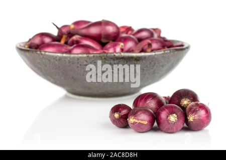 Lot of whole small red onion bulb in dark ceramic bowl isolated on white background Stock Photo