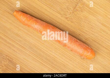 One whole fresh orange carrot flatlay on light wood Stock Photo