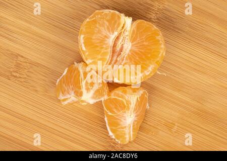 Group of one half two pieces of purified fresh orange mandarin flatlay on light wood Stock Photo