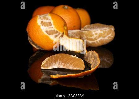 Group of four whole one half two pieces of fresh orange mandarin isolated on black glass Stock Photo