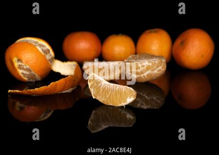 Group of five whole one half two pieces of fresh orange mandarin isolated on black glass Stock Photo