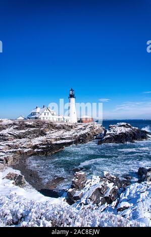 the iconic landmark Portland Headlight after a winter storm in Portland Maine on a sunny blue sky day. Stock Photo