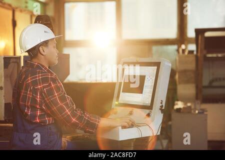 Portrait of African-American woman operating electronic machine units while working at production plant in sunlight, copy space Stock Photo