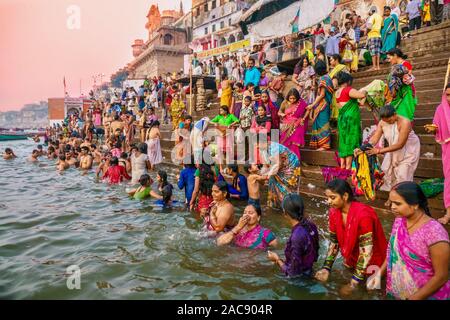 Colorful traditional clothing and Hindu religious ritual of bathing in the Ganges River from the ancient ghats of Varanasi. Stock Photo