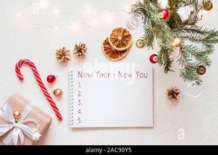 Notebook with wish list and christmas festive decor on white table. Stock Photo