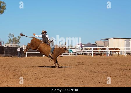 A cowboy competing in a bull riding event at an Australian country rodeo Stock Photo