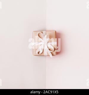 Gift box with white bow on pastel geometric background. Monochrome beige colors. Zero Waste Holiday concept. Stock Photo