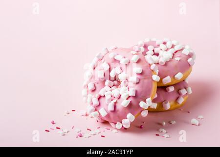 Pink glazed donuts with marshmallows on pink background. Stock Photo