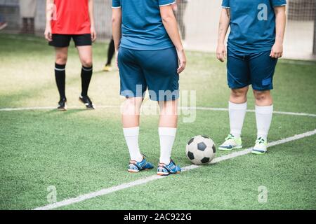 Two young active females in blue sports uniform standng in front of each other with soccer ball between them on white line Stock Photo