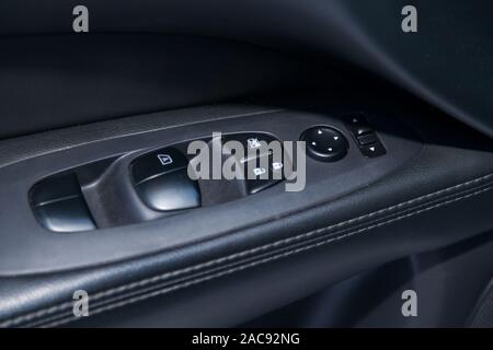 The control buttons for opening and closing windows of doors and electric controls and settings of mirrors on the door in black with leather upholster Stock Photo