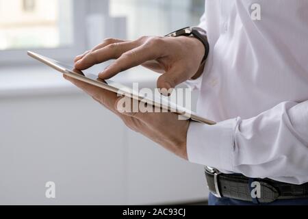 Hands of elegant businessman with tablet scrolling through online data while searching for something Stock Photo