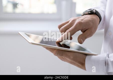 Hand of contemporary businessman with tablet pointing at screen during presentation or scrolling through online data Stock Photo