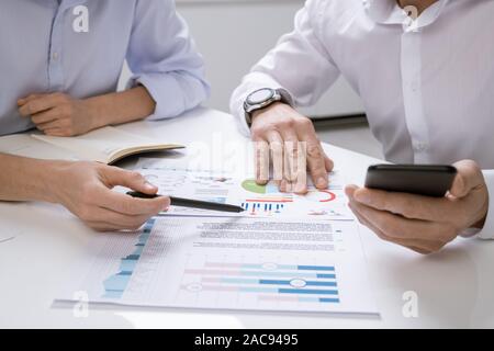 One of successful economists pointing at financial chart on paper while explaining it to colleague at meeting Stock Photo