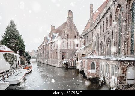 St John's Hospital, Bruges, Belgium in winter snowfall. Stunning fairy landscape with historical buildings and icy water. Christmas mood. Monochromati Stock Photo