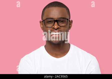 Head shot portrait African American man in glasses looking at camera, satisfied male with healthy toothy smile, satisfied teenage student in white t-s Stock Photo