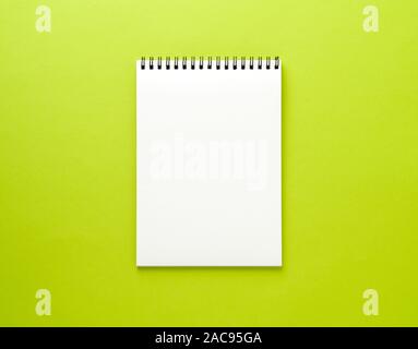 Blank notepad white page on green desk, color background. Top view,  empty space for text. Stock Photo